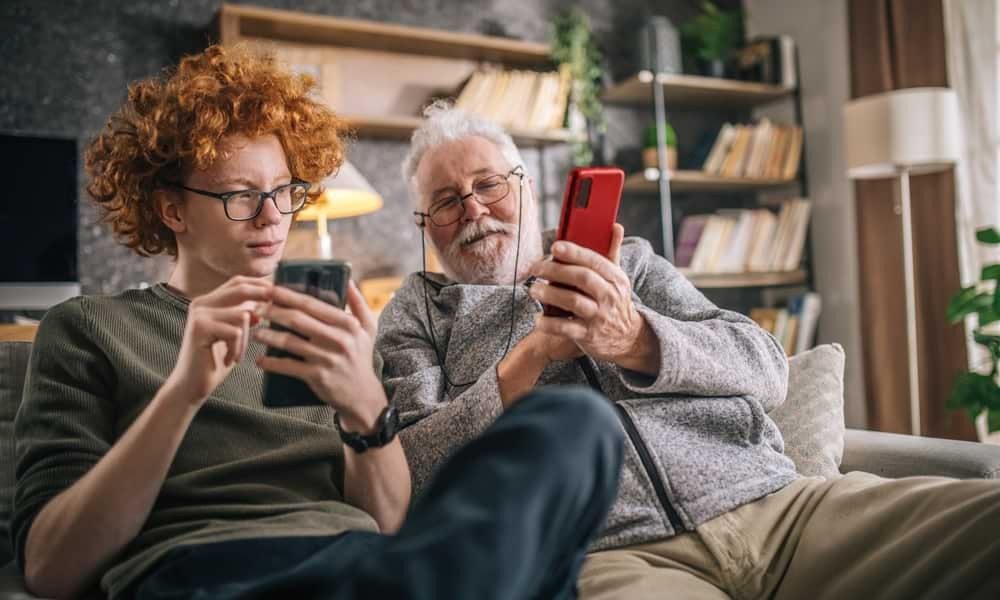 One young white man and one elderly white man using smartphones