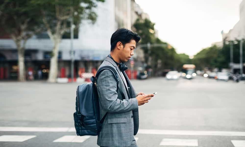 Man walking along street looking at phone