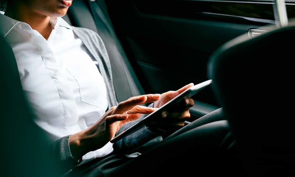 Woman in back of car on tablet