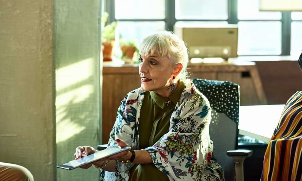 Senior business woman showing something on tablet to someone off camera