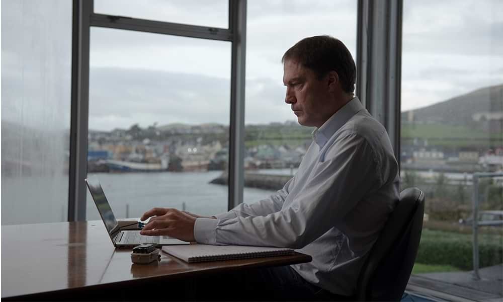 Man working on laptop from home studio with baby daughter on lap