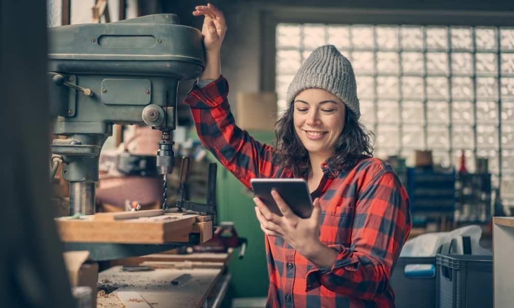 Woman looking at laptop while working in carpentry space